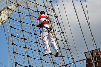 Man climbing rigging net on tall sailing ship