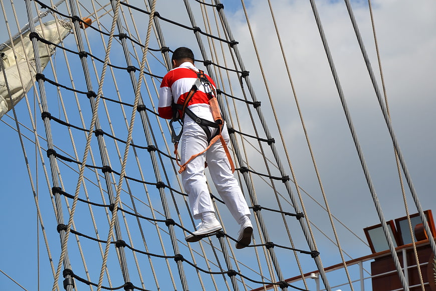 Man climbing rigging net on tall sailing ship