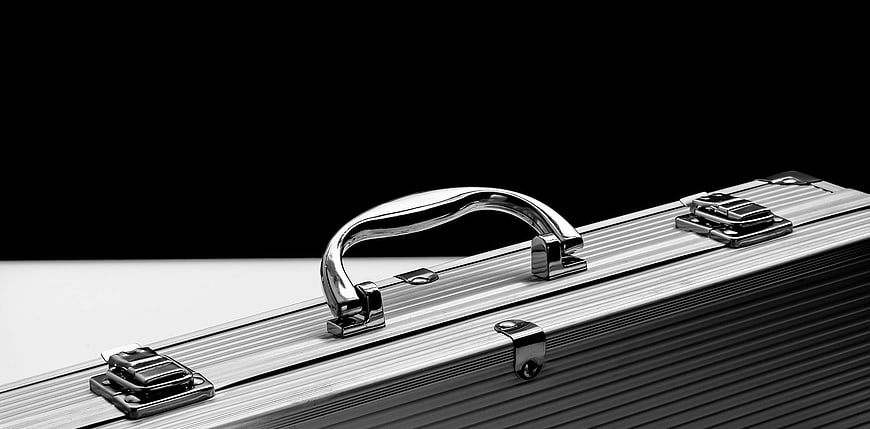 Close-up of silver aluminum briefcase with chrome handle on black background