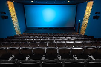 Empty modern cinema auditorium with blue screen and rows of seats