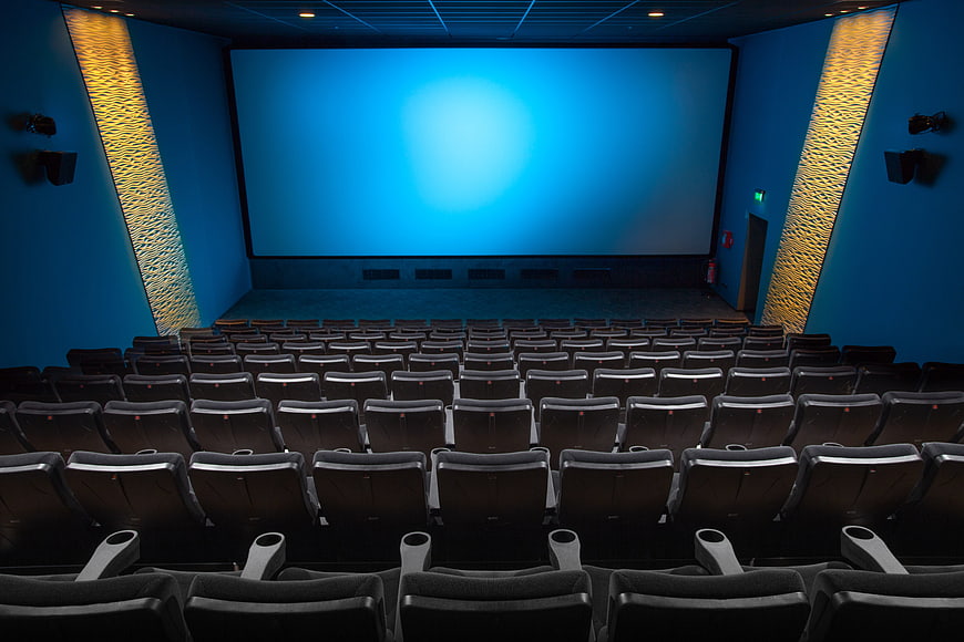 Empty modern cinema auditorium with blue screen and rows of seats