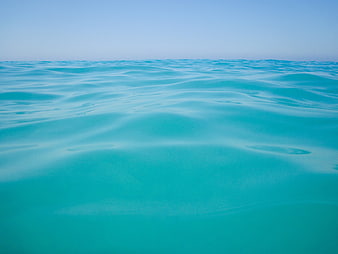 Abstract turquoise water surface with gentle ripples and blue sky