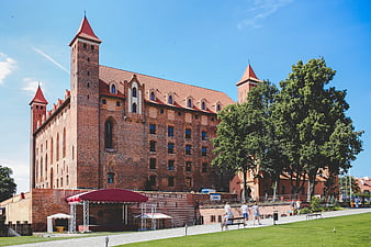 Historic red brick castle in Poland with green lawn