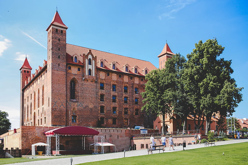 Historic red brick castle in Poland with green lawn