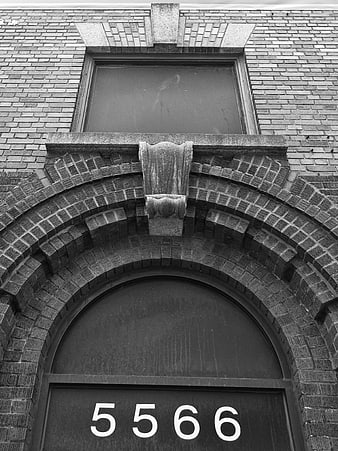 Black and white brick building facade with arched doorway and number 5566