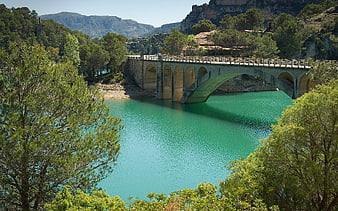 Turquoise River Under Stone Arch Bridge in Mountain Valley
