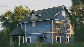 Blue wooden house with gazebo in overgrown garden