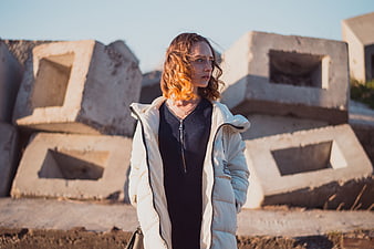 Woman in White Puffer Jacket Standing by Concrete Blocks