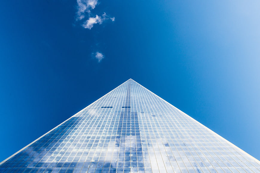 Low angle view of modern glass skyscraper against blue sky