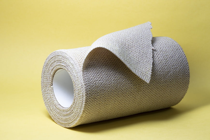Roll of Medical Gauze Bandage on Yellow Background