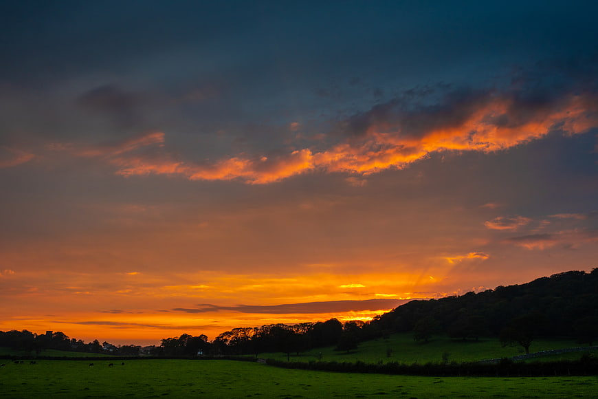 Dramatic Orange Sunset Over Green Rolling Hills