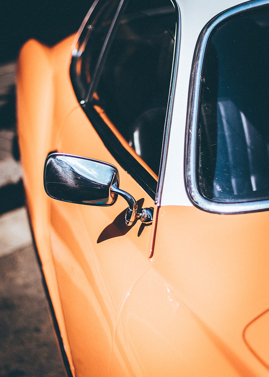 Close-up of vintage orange car side mirror and window