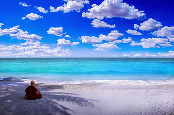 Buddhist monk meditating on a tropical white sand beach