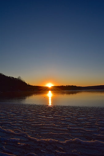 Sunset over frozen lake with ice texture and golden reflection