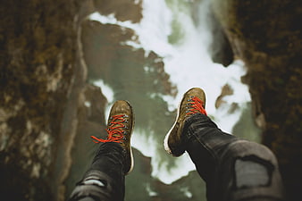 First-person view of hiking boots dangling over a rushing river