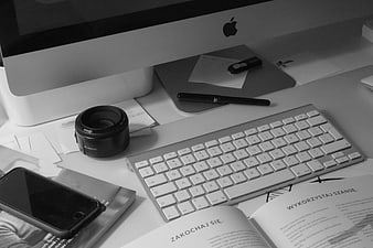 Black and white workspace with iMac, keyboard, and camera lens