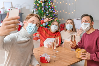Friends taking a selfie with face masks at a Christmas party