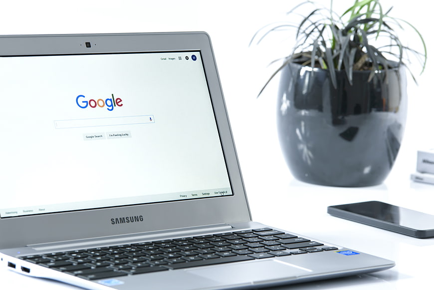 Silver laptop displaying Google search engine on white desk