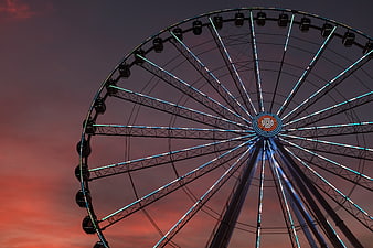Illuminated Ferris Wheel Against Dramatic Sunset Sky