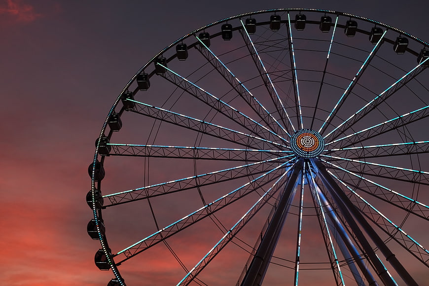 Illuminated Ferris Wheel Against Dramatic Sunset Sky