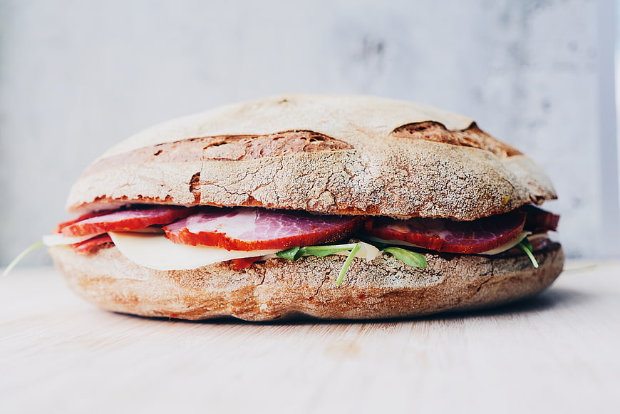 Close-up of rustic ham and cheese sandwich on wooden table