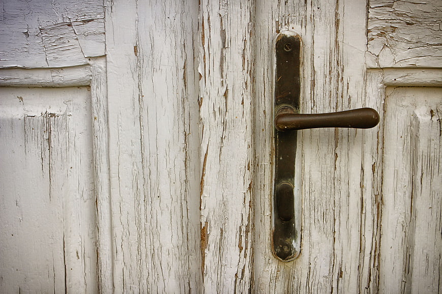 Close-up of weathered white wooden door with vintage handle