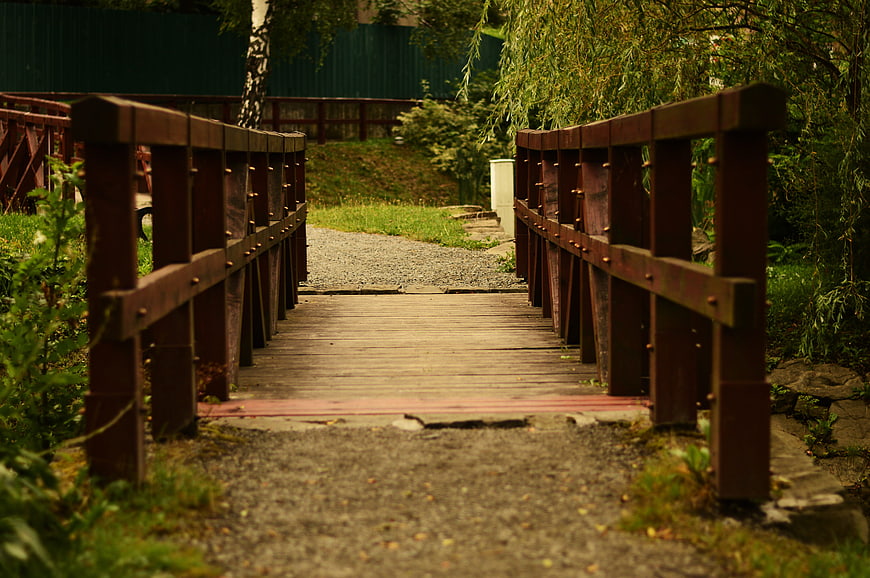 Wooden bridge leading to a gravel path in a garden