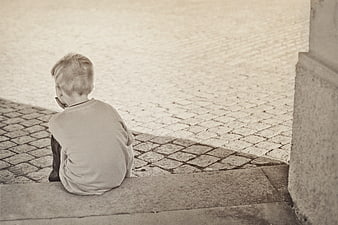 Lonely boy sitting on stone steps in sepia tone