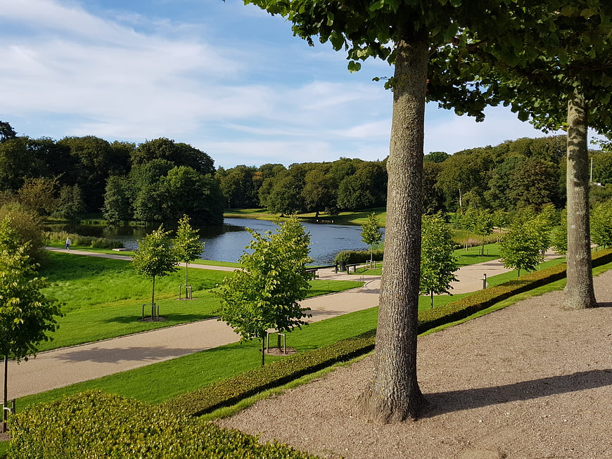 Serene park landscape with lake, trees, and walking paths