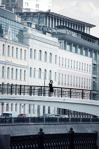 Woman in Black Dress Standing on Urban Bridge