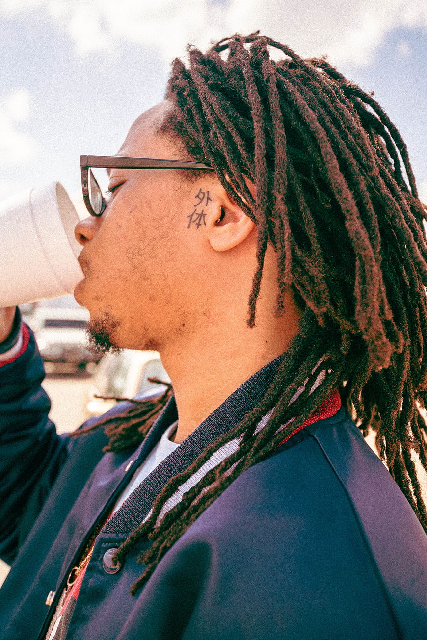 Man with Dreadlocks Drinking Coffee Outdoors