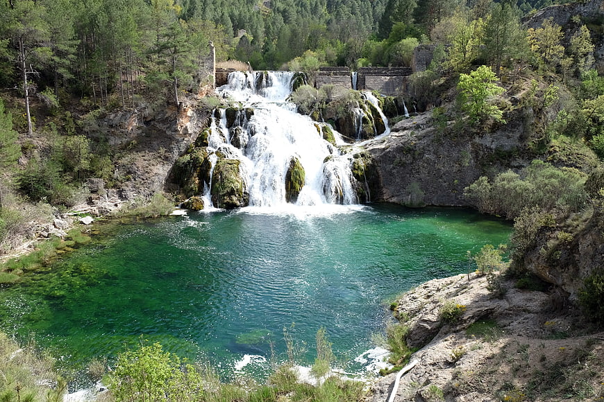 Turquoise waterfall cascading into a clear pool surrounded by forest