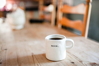 White coffee mug with word BEGIN on wooden table
