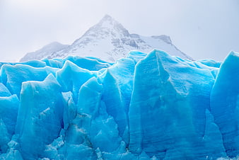 Vibrant Blue Glacier Ice with Snowy Mountain Background
