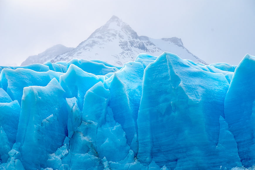 Vibrant Blue Glacier Ice with Snowy Mountain Background