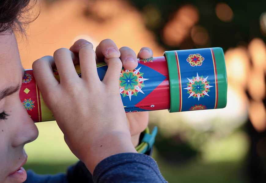 Child Looking Through Colorful Kaleidoscope Toy