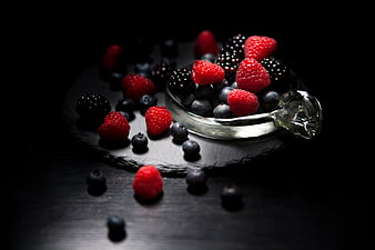 Dark moody mixed berries in glass bowl on slate