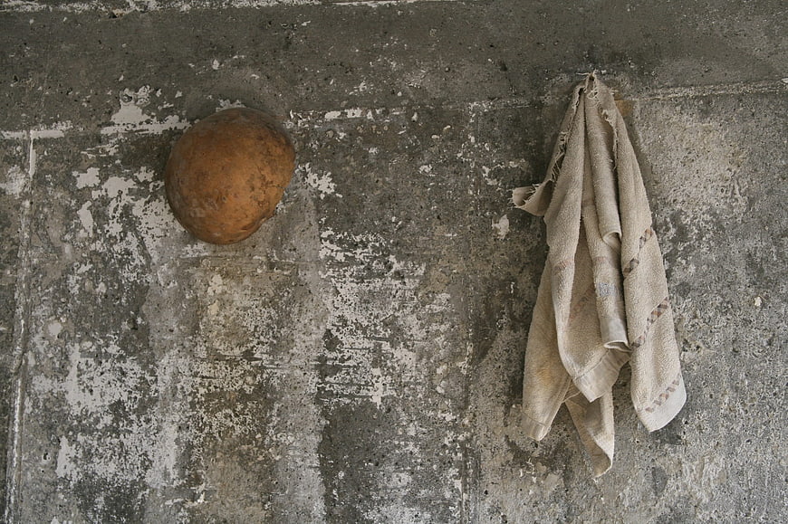 Rusty bucket and towel on weathered concrete wall