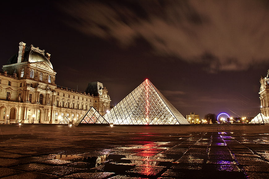 Illuminated Louvre Pyramid at Night with Wet Reflections