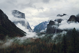 Misty mountain valley with autumn forest and waterfall