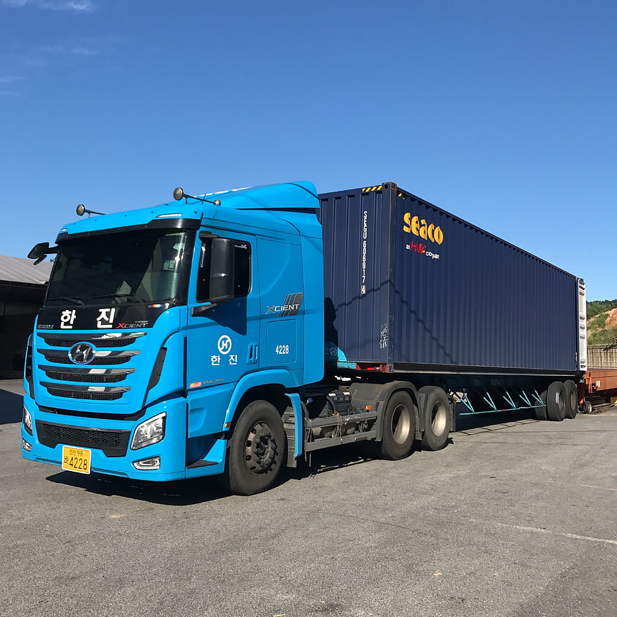 Blue Hyundai Xcient Truck Hauling Shipping Container
