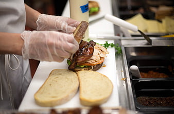 Chef preparing gourmet sandwich with bacon and turkey