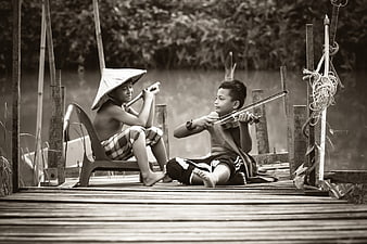 Two Boys Playing Violin and Flute on Wooden Dock
