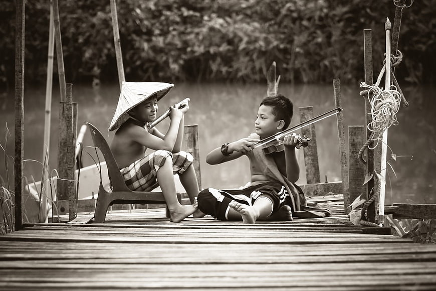 Two Boys Playing Violin and Flute on Wooden Dock