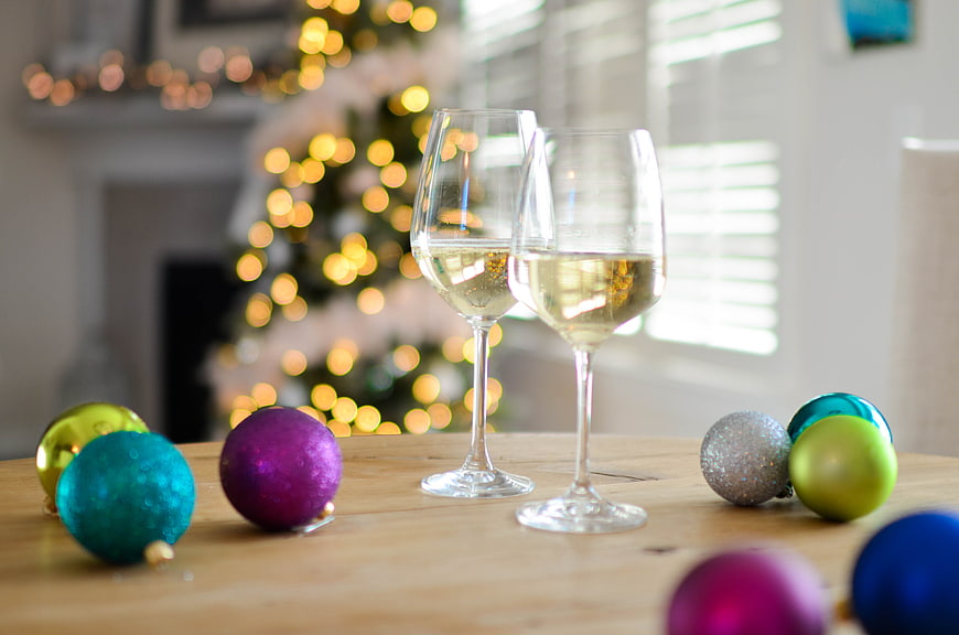 Two Glasses of White Wine with Christmas Ornaments on Table