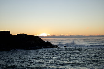 Silhouette of rocky coastline at golden hour sunset