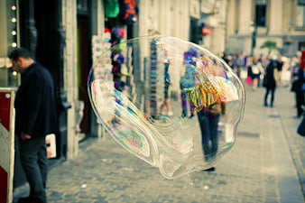 Giant Soap Bubble Floating on Cobblestone Street
