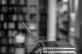 Black and white laptop on desk with candle in library