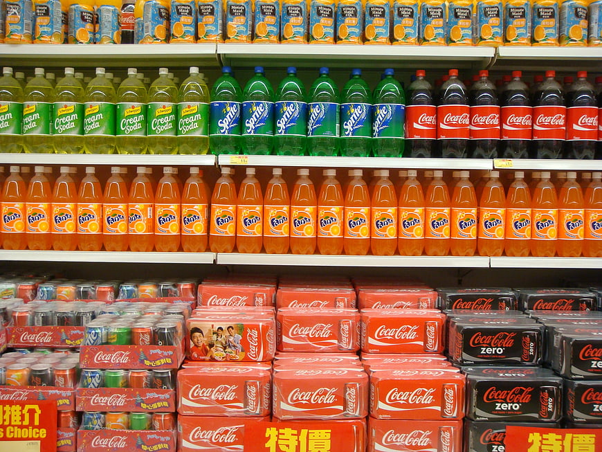 Supermarket shelves stocked with colorful soda bottles and cans