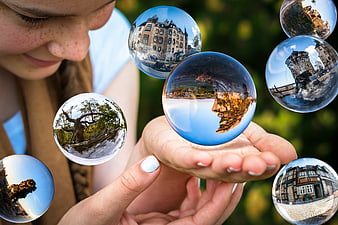 Woman holding glass spheres with European landmarks and landscapes